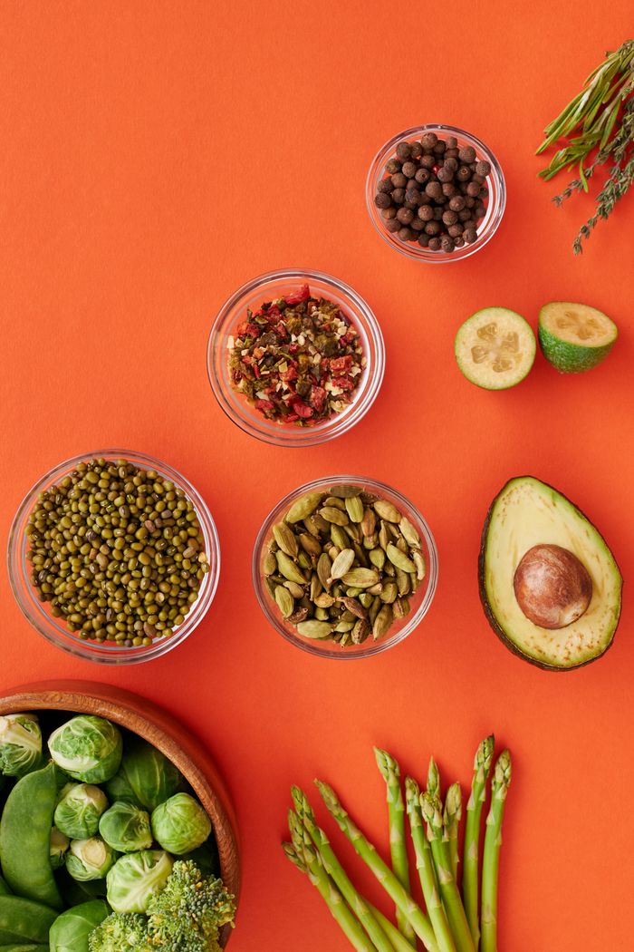 A vibrant flatlay showcasing fresh vegetables and spices on an orange background.